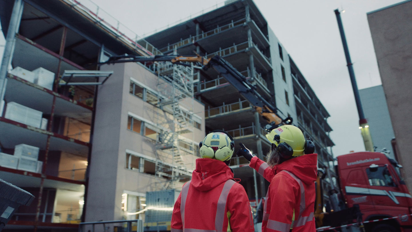 To ingeniører på byggeplass, ser på bygning. Foto