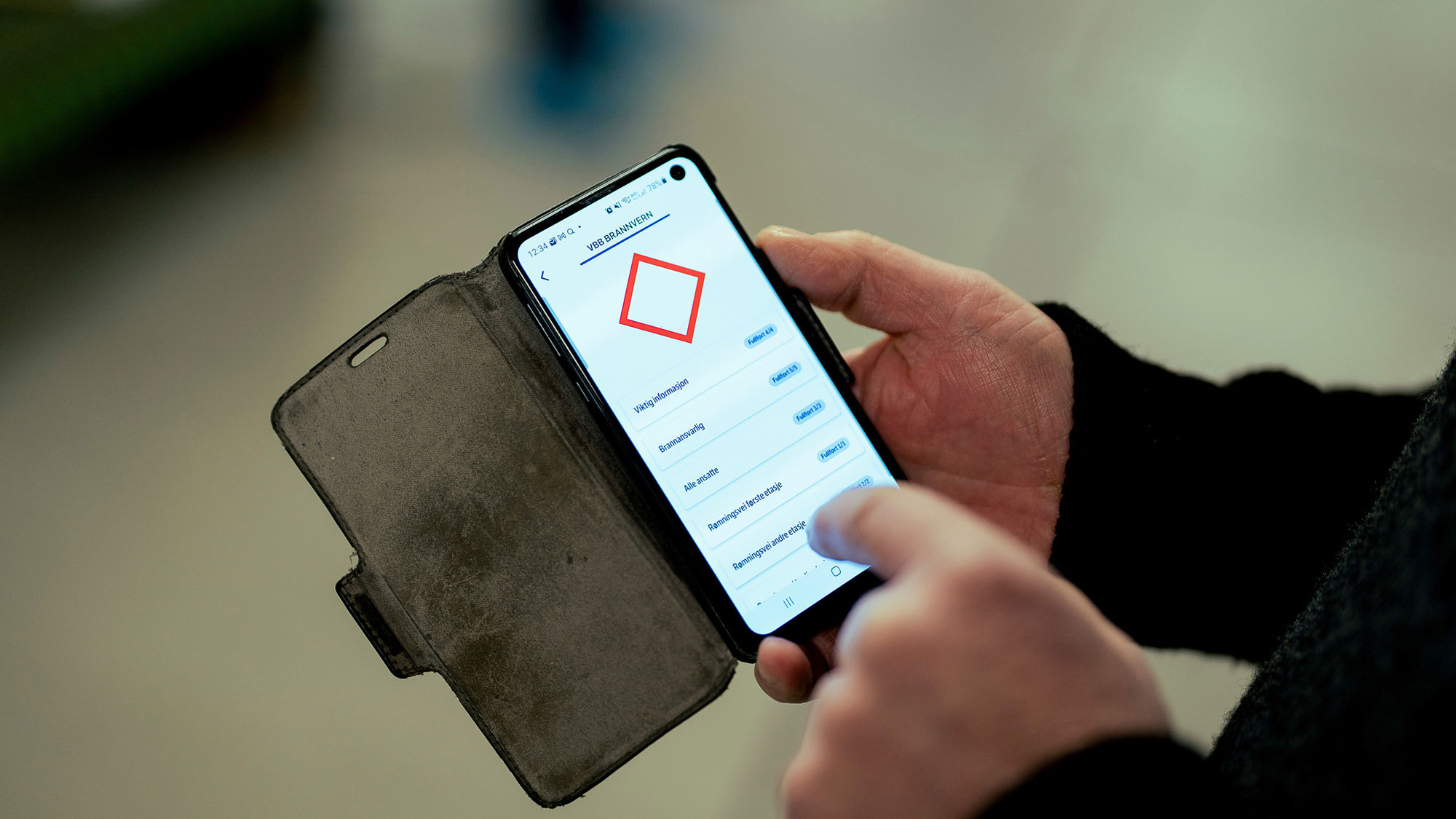 Mann holder telefon og trykker. Foto.