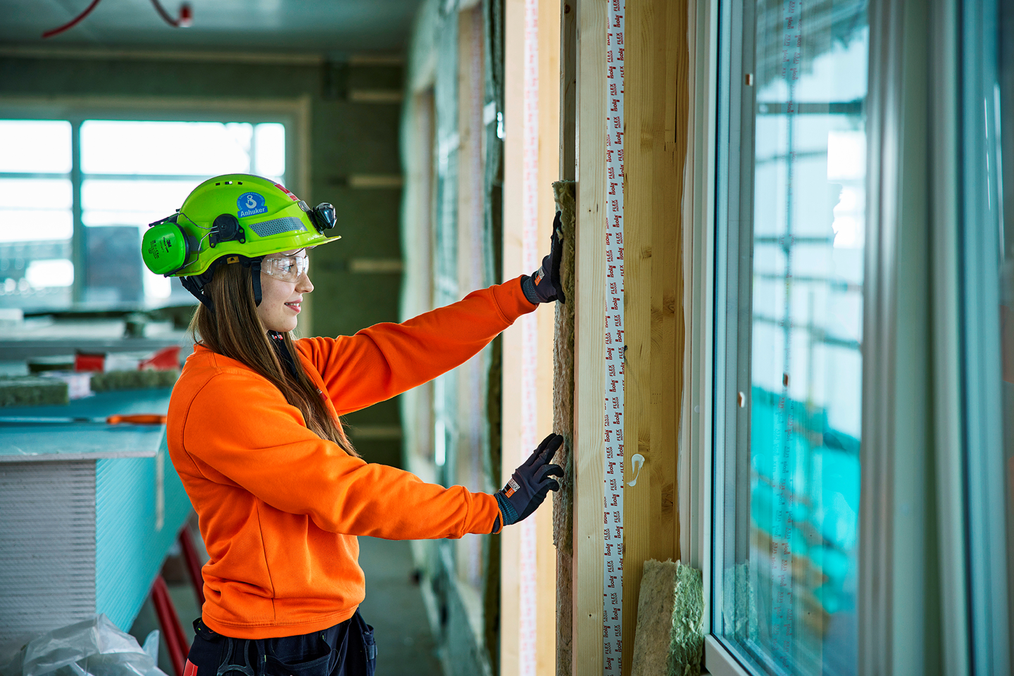 Bilde av ung kvinnelig lærling i veidekke på byggeplass. Foto