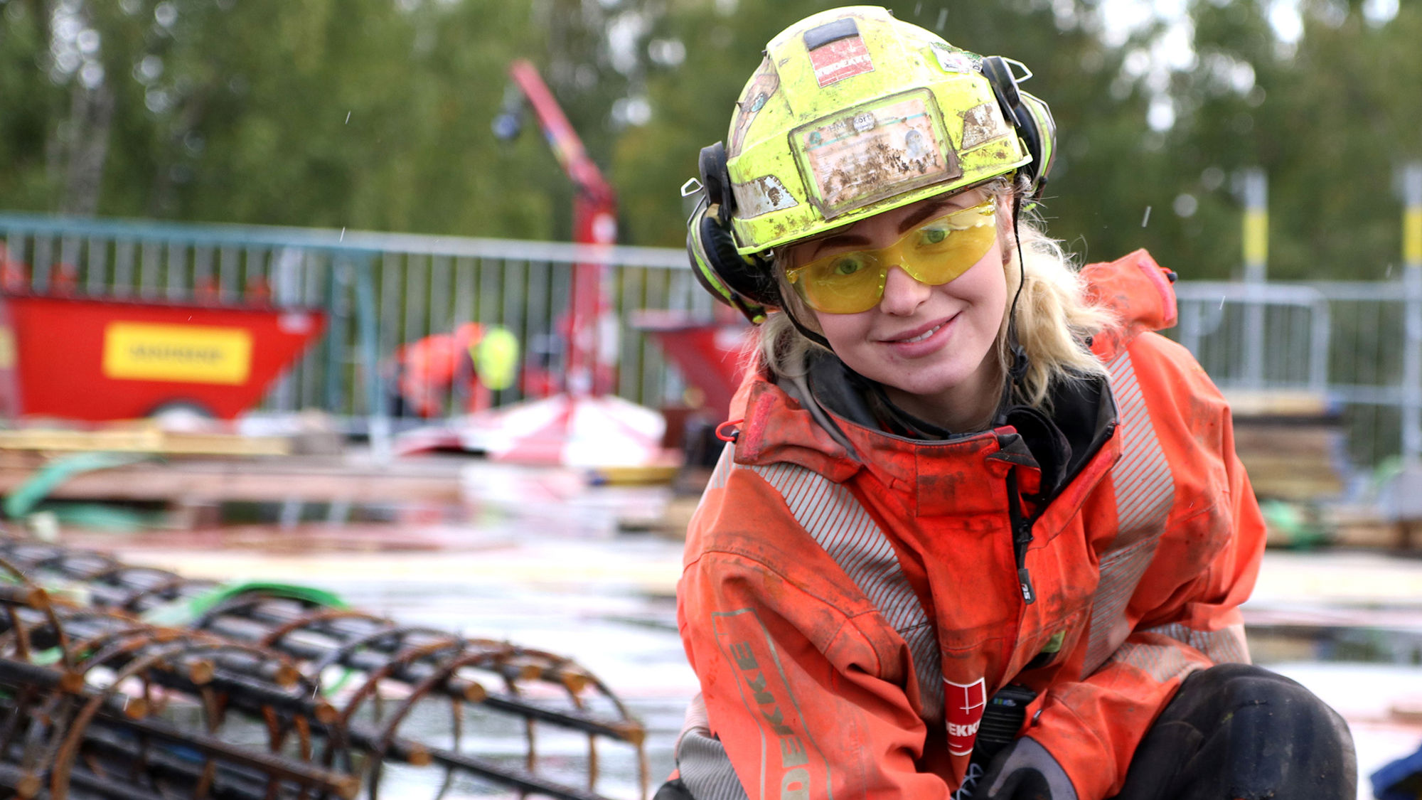 Kvinne på byggplass jobber med betong. Foto.