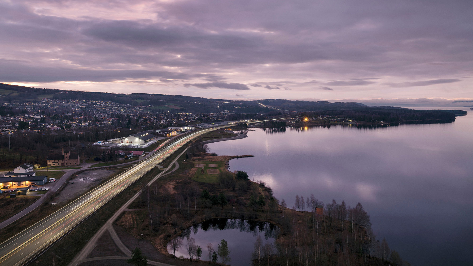 Utsikt over E6 og Mjøsa ved Brumunddal i skumringstimen. Foto.