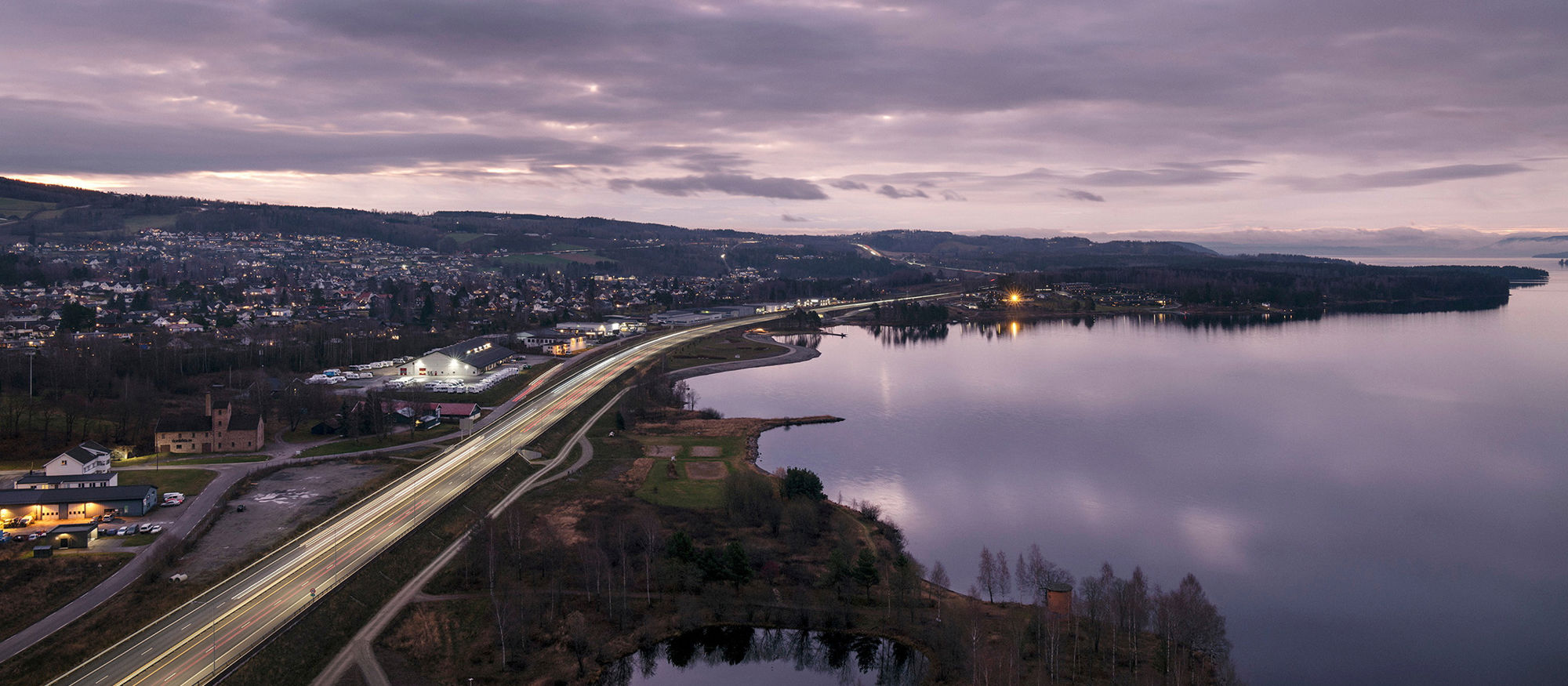 Utsikt over E6 og Mjøsa ved Brumunddal i skumringstimen. Foto.